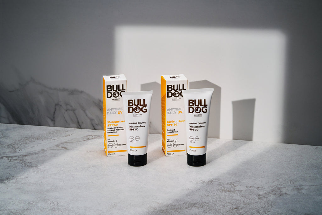 Two tubes and two boxes of Anytime Daily Moisturiser SPF 30 are on a light grey surface, set against a grey and white background. Shadows from the products highlight their UVA/UVB protection.