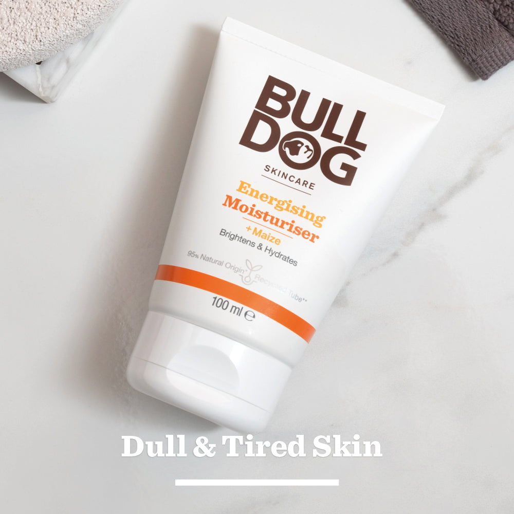 A tube of Energising Moisturiser for men rests on a white surface, with Dull & Tired Skin below. The product claims to brighten and hydrate using ingredients of natural origin.