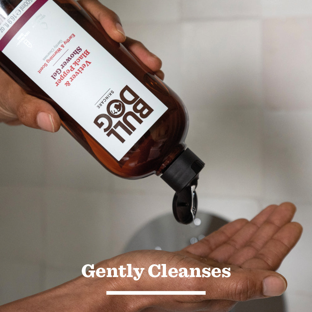 A hand pours Vetiver & Black Pepper Shower Gel from a brown bottle into the palm, with Gently Cleanses below, highlighting its natural fragrance designed for mens skincare.