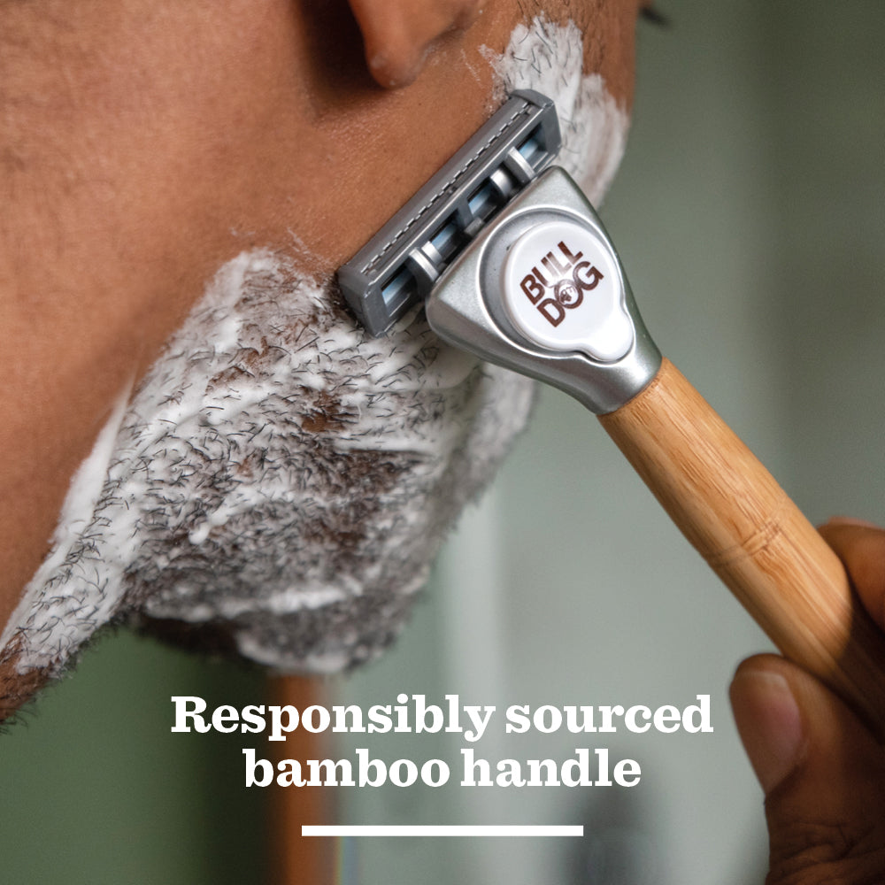 Close-up of a person shaving with a Bulldog Razor featuring a responsibly sourced bamboo handle and Sensitive Steel Blades. Shaving cream covers the razor, while “Responsibly sourced bamboo handle” appears at the bottom.