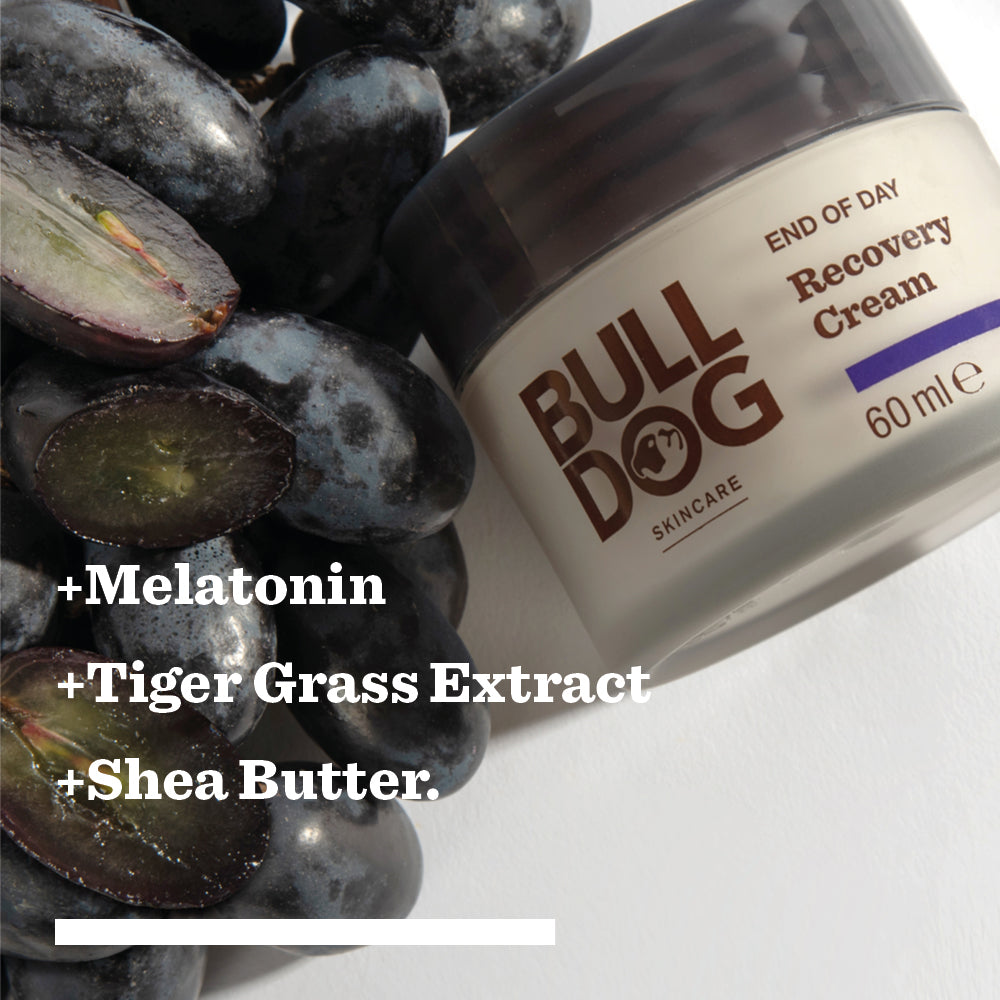A jar of End of Day Recovery Cream sits beside dark grapes. The image text highlights its key ingredients: Melatonin, Tiger Grass, and Shea Butter for effective nightly recovery.