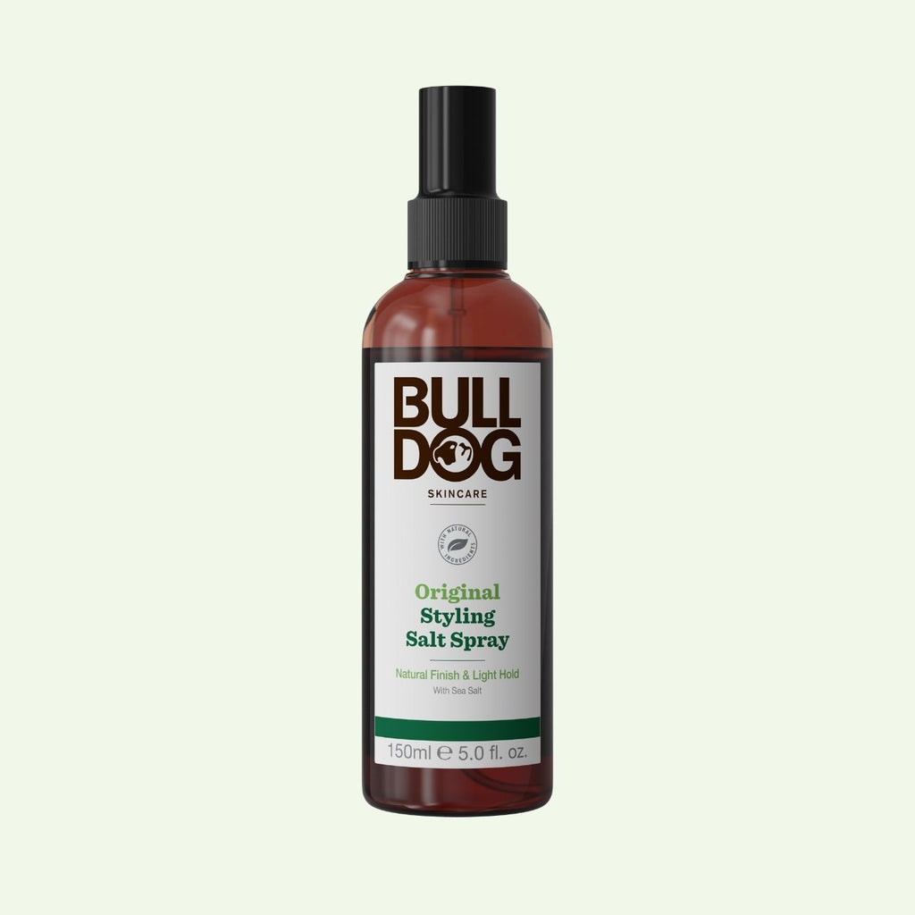 A 150ml bottle of Original Hair Styling Salt Spray, with naturally derived Mediterranean sea salt, a black spray cap, and a white-green label, shown on a light green background.